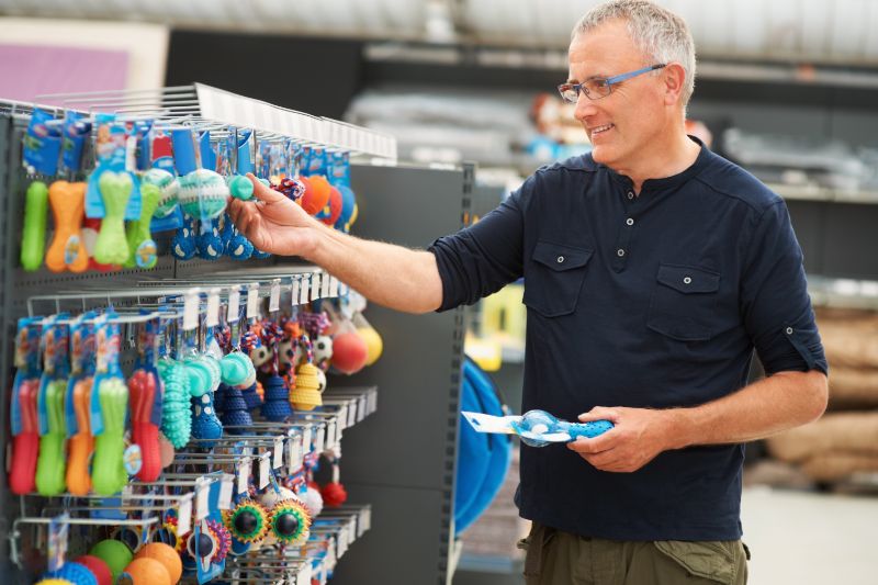 A man in a blue shirt shops for pet toys to help shelter animals. 